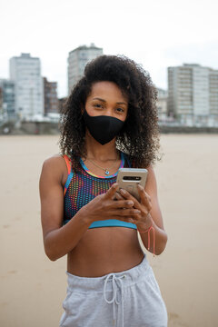 Urban Fit Sporty Woman Using Smartphone Workout App For Training Outdoors At City Beach Under Coronavirus Covid Pandemic Restrictions. Gijon, Asturias, Spain.