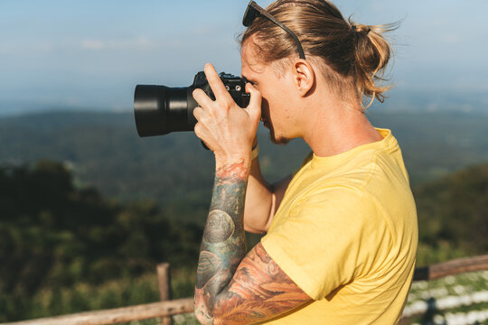 Man photographer in yellow tshirt making photo of beautiful landscape
