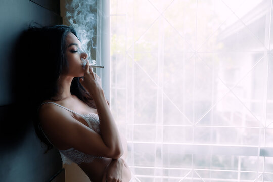  young female wearing underwear smoking cigarette indoors