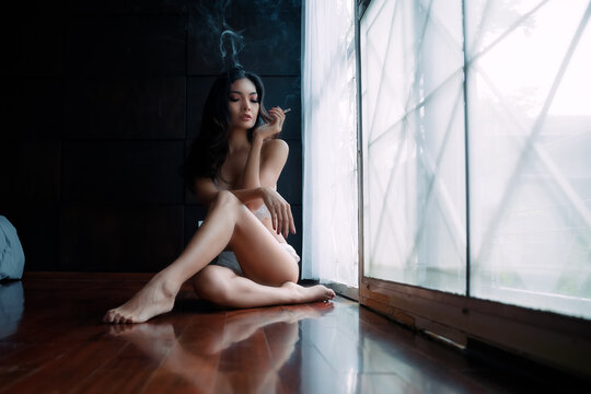  young female wearing underwear smoking cigarette indoors