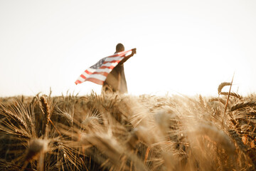 African american young man holding USA national flag through wheat field