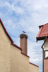 A pair of storks builds a nest on a chimney at home against a blue spring sky. Kaliningrad region, Russia - 448574682