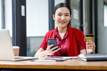 Portrait of Happy cheerful smiling young adult female using credit card and smartphone laptop doing online shopping or e-shopping entrepreneur making online payment paying for employed and service. 