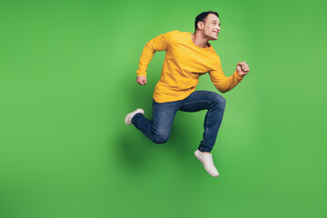 Fototapeta na wymiar Portrait of dreamy handsome guy jump fly enjoy run fast on green background