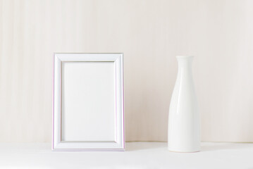 White vase and white photo frame in a light interior