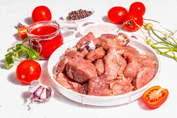 Raw pork pieces, tomatoes, spices, and herbs