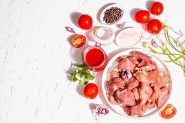 Raw pork pieces, tomatoes, spices, and herbs