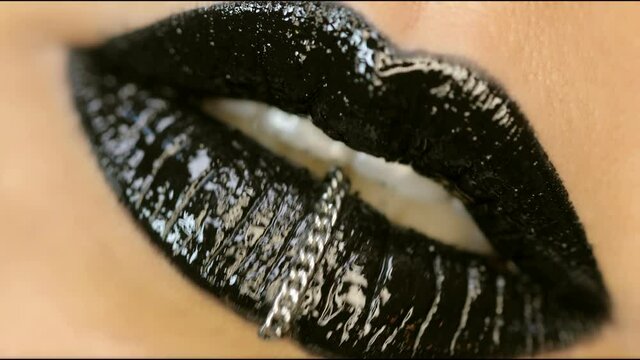 Closeup of a beautiful woman lips with beautiful black makeup and piercing sending air kiss . Close up of girl's mouth having flirty emotions and sending air kiss 