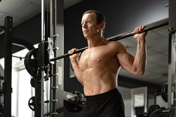 Fototapeta na wymiar Senior man working out at the gym doing squats