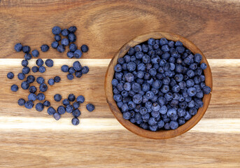 Fresh Blue Blueberries in a wooden plate and scattered on a wooden table background. Top view. fresh and healthy snack
