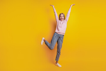 Photo of carefree funny girl stand one leg raise hands on yellow background