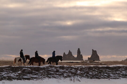 people riding horses in the frozen beach in Iceland