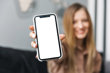 Young woman holds out mobile phone with white screen