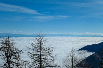 A panoramic view from the top of Alpine peak in Austria. The whole area is shrouded in thick clouds. A few peaks popping out from the clouds. High mountain chains in the back. Carpet from the clouds