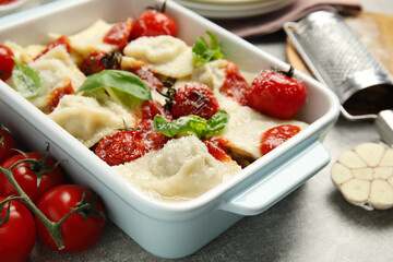 Tasty ravioli with tomato sauce served on grey table, closeup