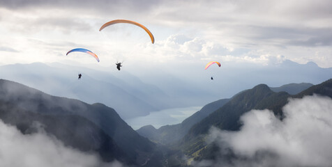 Adventure Composite Image of Paraglider Flying up high in the valley near Mountains. Sunny Summer Cloudy Sky. Aerial Background from British Columbia, Canada. Extreme Sport Concept.
