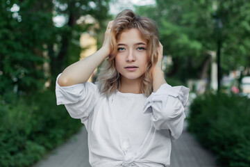 Portrait of a beautiful young woman in white clothes on the alley of the city