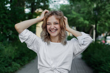 Portrait of a beautiful young woman in white clothes on the alley of the city