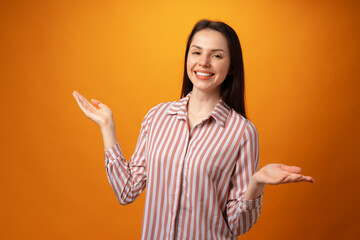 Young positive woman points fingers at copy space