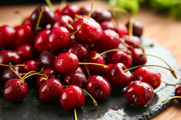 Ripe juicy red cherries lie on a black surface, washed with water