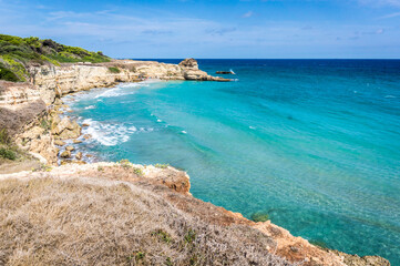 The Punticeddha Beach or Spiaggia Punticeddha of Sant'Andrea, Salento Adriatic sea coast, Apulia, Italy. Beautiful sandy sea coast of Puglia with blue water, cliffs on a Summer day, top view