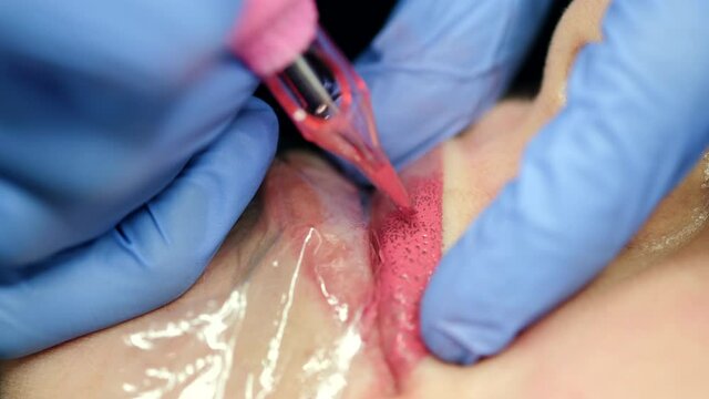 Micro pigmentation of lips process. Female permanent make up master holding machine applying pigment to woman client lips. Beauty and aesthetic treatment concept