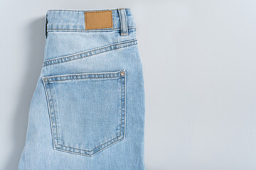 Mock up empty detailed close-up of blank grungy leather label on blue denim suitable on gray background with copy space suitable for your design, logo, advertising. Sample. Flat lay
