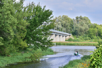 Obraz premium Bridge over the river between trees on a sunny day. Summer. Day.