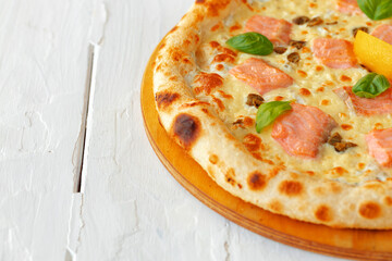 Pizza with baked salmon on wooden table