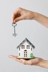 a beautiful small model of a house in women's hands, a house in miniature for an architectural project or a design site, a new house or apartment, a dream about your real estate, the keys to the house