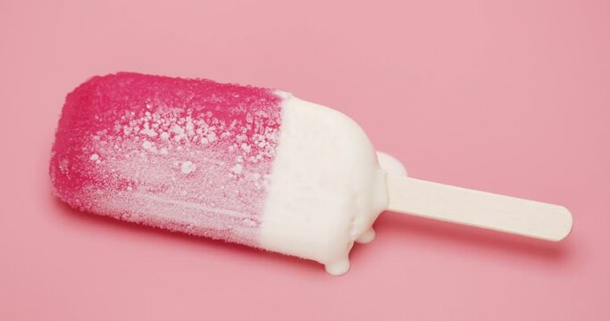Close-up detail Top view, Time-lapse ice cream strawberry popsicle stick melting isolated on the floor pink background.
