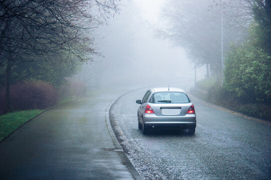 A car moving in a fog in a city - concept of a dangerous hazardous driving conditions, limited visibility