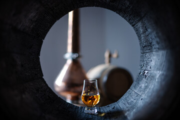 A glass of whiskey in oak barrel