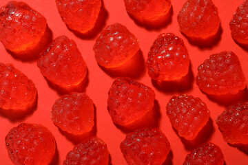 Delicious gummy raspberry candies on red background, flat lay
