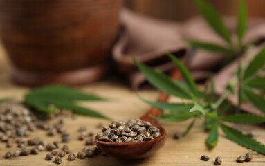 Organic hemp seeds and leaves on wooden table, closeup. Space for text