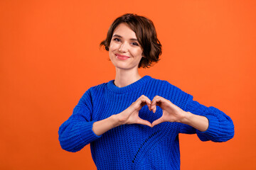 Photo of flirty brunette millennial lady show heart wear blue pullover isolated on orange color background
