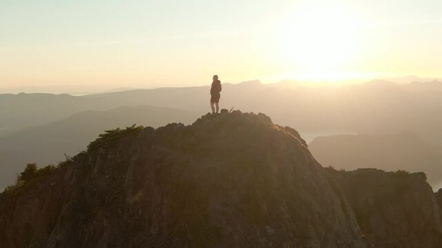 Adventurous Caucasian Woman Hiking on top of a Rocky Mountain Cliff. Sunny Summer Sunset. Mnt Brunswick Hike, North of Vancouver, British Columbia, Canada.
