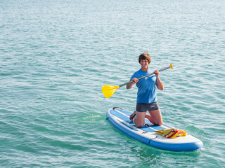 Paddle boarder. Sportsman on knees paddling on stand up paddleboard. SUP surfing. Active lifestyle. Outdoor recreation. Vacation on seaside.