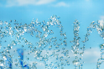 Spray drops of fountain on blue sky background