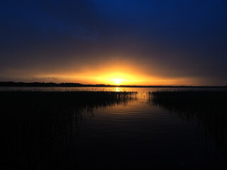 Fototapeta premium Sunset sky and water. Peaceful evening. Reed silhouettes. Travel and leisure
