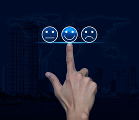 Hand pressing excellent smiley face rating icon over world map, modern city tower and skyscraper, Business customer service evaluation and feedback rating concept, Elements of this image furnished by 