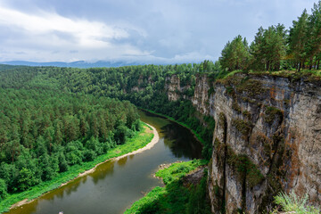 Fototapeta na wymiar A river in a mountain gorge, aerial view, filmed from a drone. River at the foot of a stone cliff. The coast is covered with forest. View of the mountain gorge.