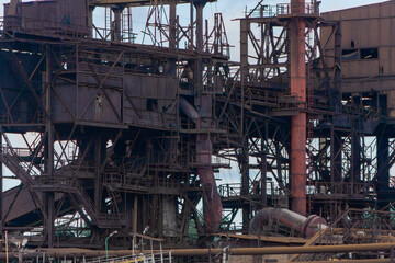 Abandoned structure of an old metallurgical plant. The old block of the iron-smelting plant. Dark iron staircases are transitions between the factory premises.