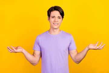 Photo of clueless uncertain loser guy shrug shoulders wear purple t-shirt isolated yellow color...