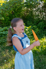Girl is eating fresh carrots in the garden. 