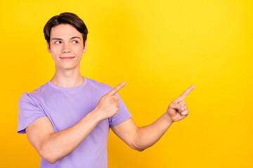 Portrait of attractive cheerful guy demonstrating copy space place ad advert solution way isolated over bright yellow color background