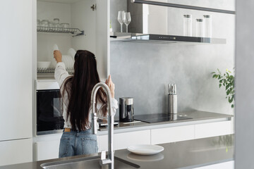 Woman putting white plate into spacious storage drawer