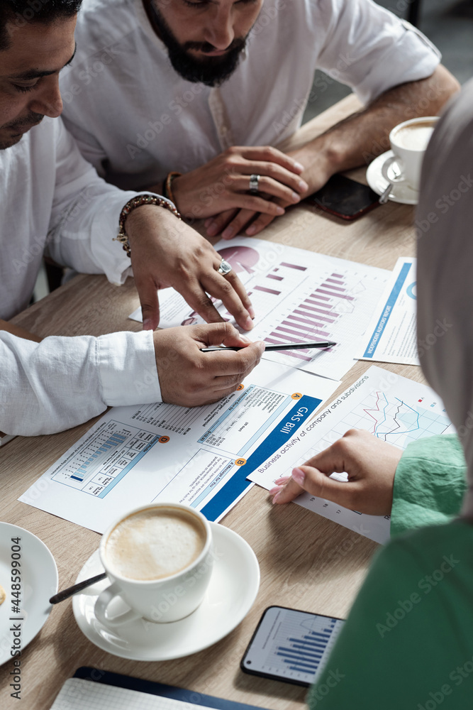 Wall mural Group of contemporary Muslim business people discussing financial papers