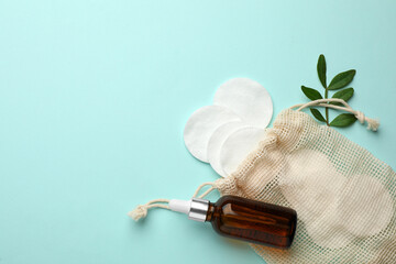 Cotton pads, leaf and makeup removal product on light blue background, flat lay. Space for text