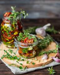 Dried tomatoes with herbs and spices. Seasonal appetizer of vegetables. Rosemary, garlic, thyme on a wooden background. Fresh harvest. A can of baked tomatoes. Italian food. Italian cuisine